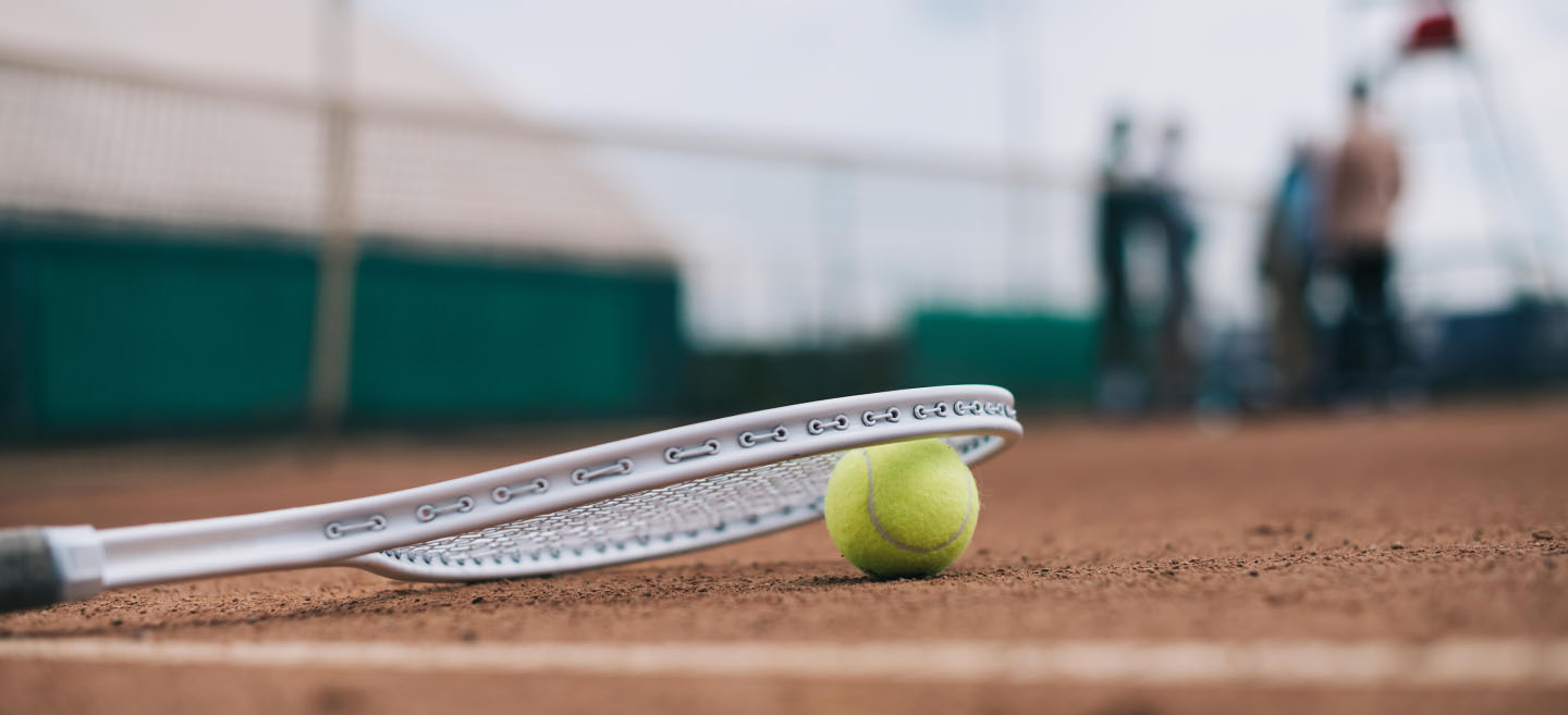 Tennisschläger und Ball auf dem Sandplatz